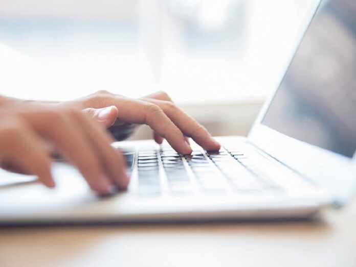 Close-up of male hands typing on laptop keyboard