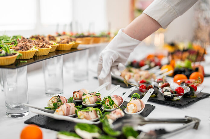 A gloved hand arranges an elegant assortment of gourmet appetize