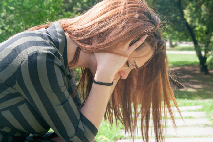 Depressed girl sitting on bench in park