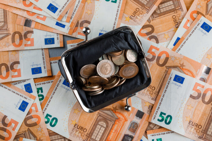 Financial concept with coins in purse on banknote and plaster background flat lay.