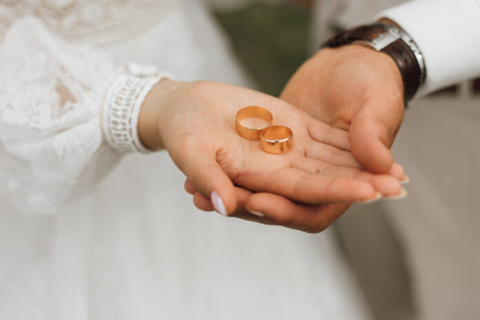 Golden bands in the hands of groom and bride, wedding day